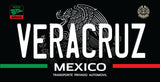 A black license plate style sign featuring the word 'VERACRUZ' in large white letters, 'MEXICO' below, and 'TRANSPORTE PRIVADO AUTOMOVIL' underneath. The design includes the Mexican coat of arms in gray, green and red horizontal bars, and two circular Mexican emblem marks at the top corners.